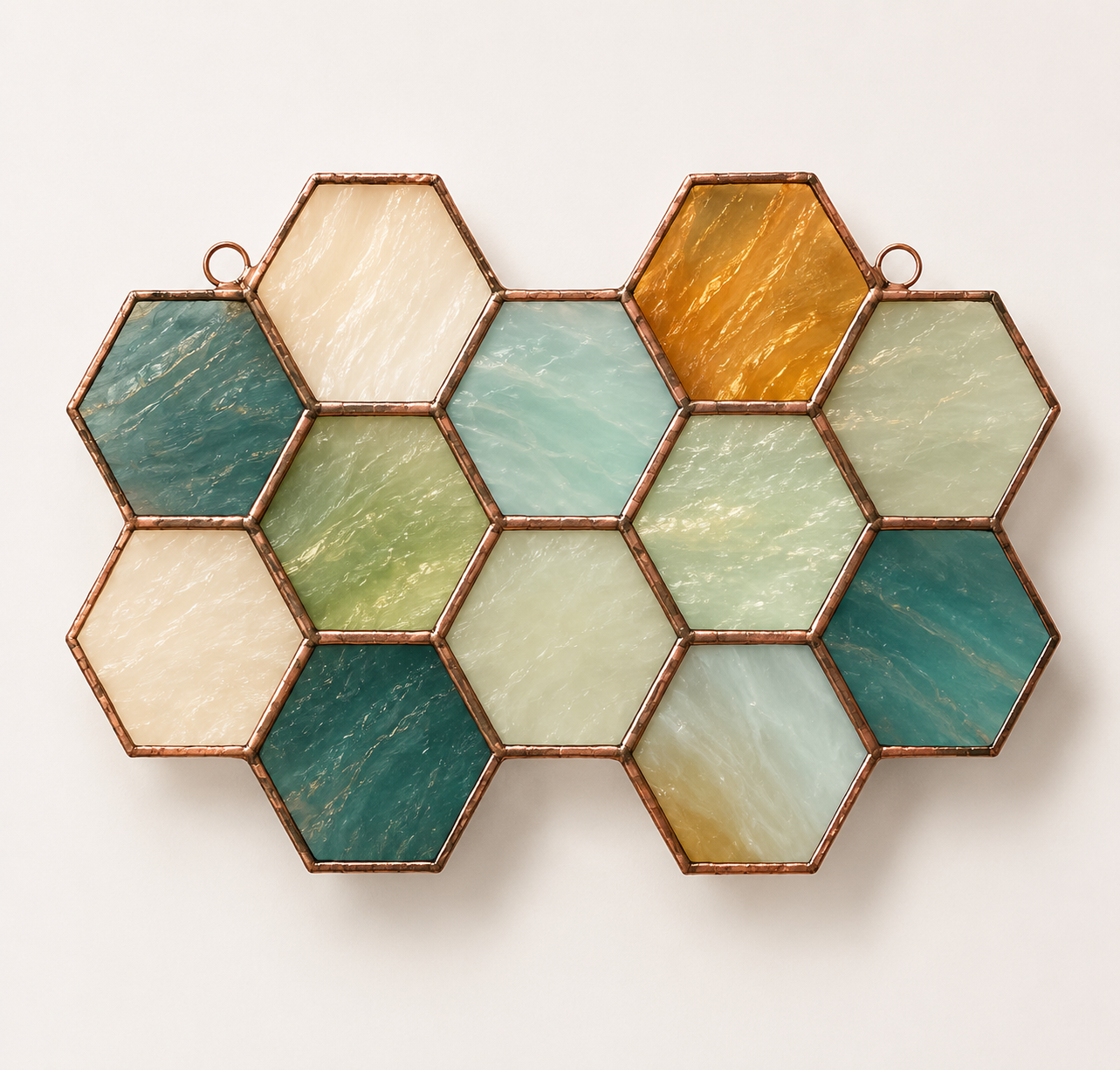 Soft seafoam and honey stained glass honeycomb suncatcher photographed on a light backdrop.