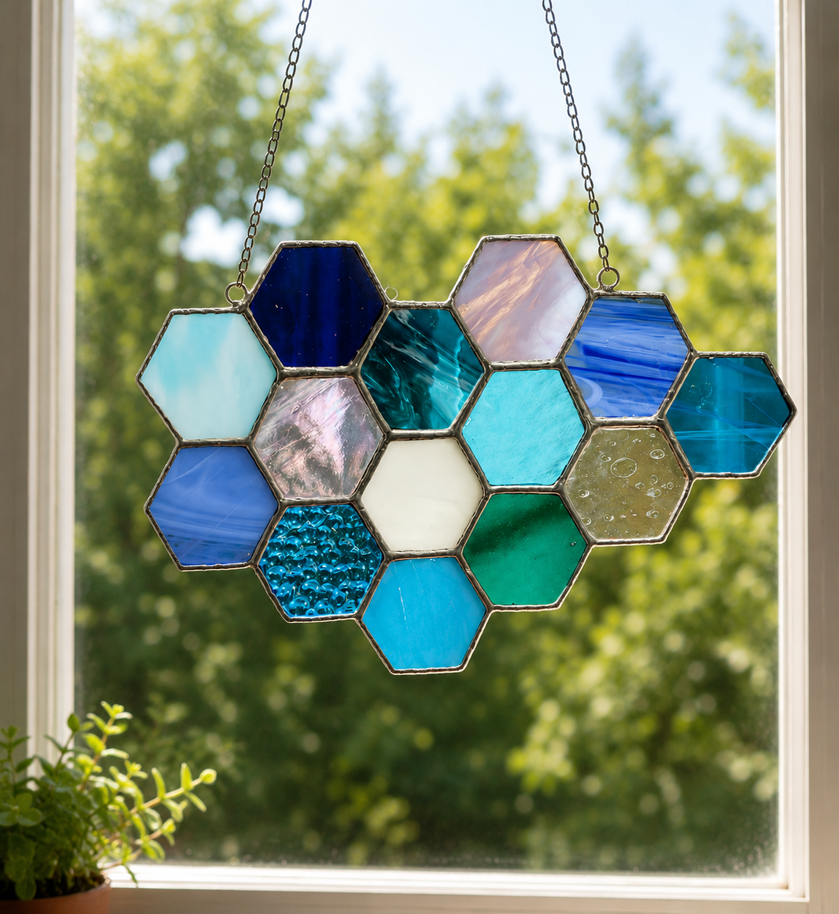 Blue and aqua stained glass honeycomb suncatcher hanging in a bright window.